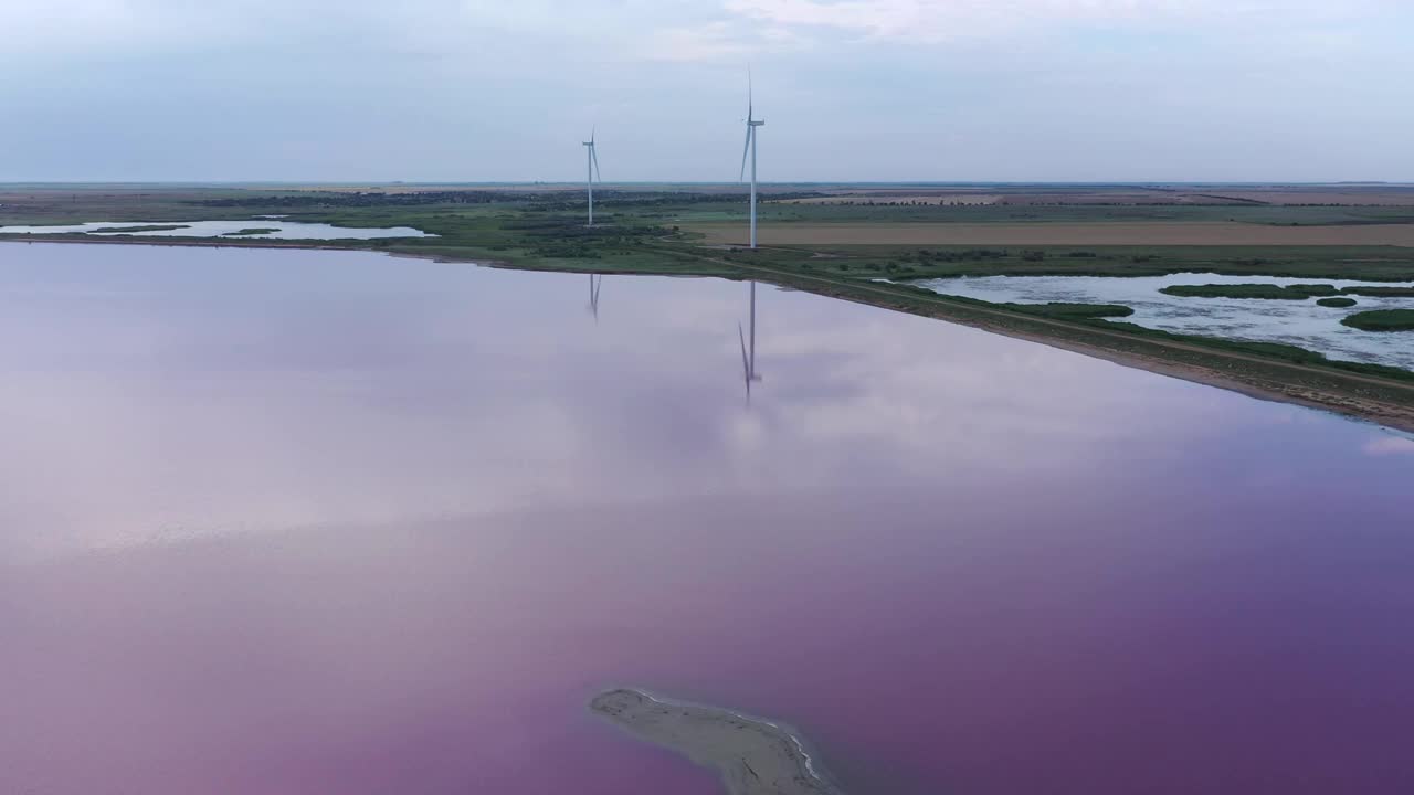 一个美丽的粉红色湖岸边的风力涡轮机的鸟瞰图。视频素材