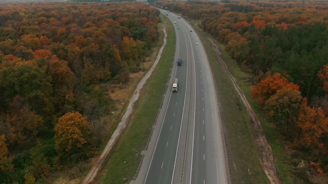 狭窄蜿蜒道路上汽车的鸟瞰图。秋天五颜六色的树在路边。视频素材