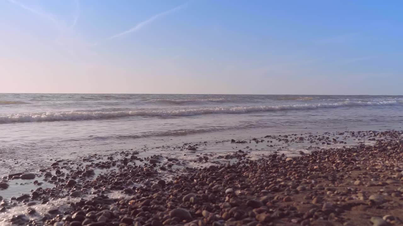 一个苗条的女人走在沙滩上的海浪上。视频素材