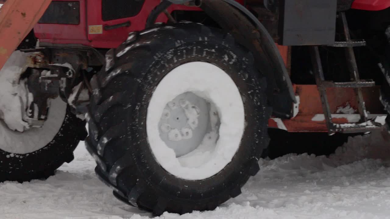 冬天，一辆带着黄色铲斗的拖拉机在街上铲雪。道路清洁援助，工业。缓慢的莫视频素材