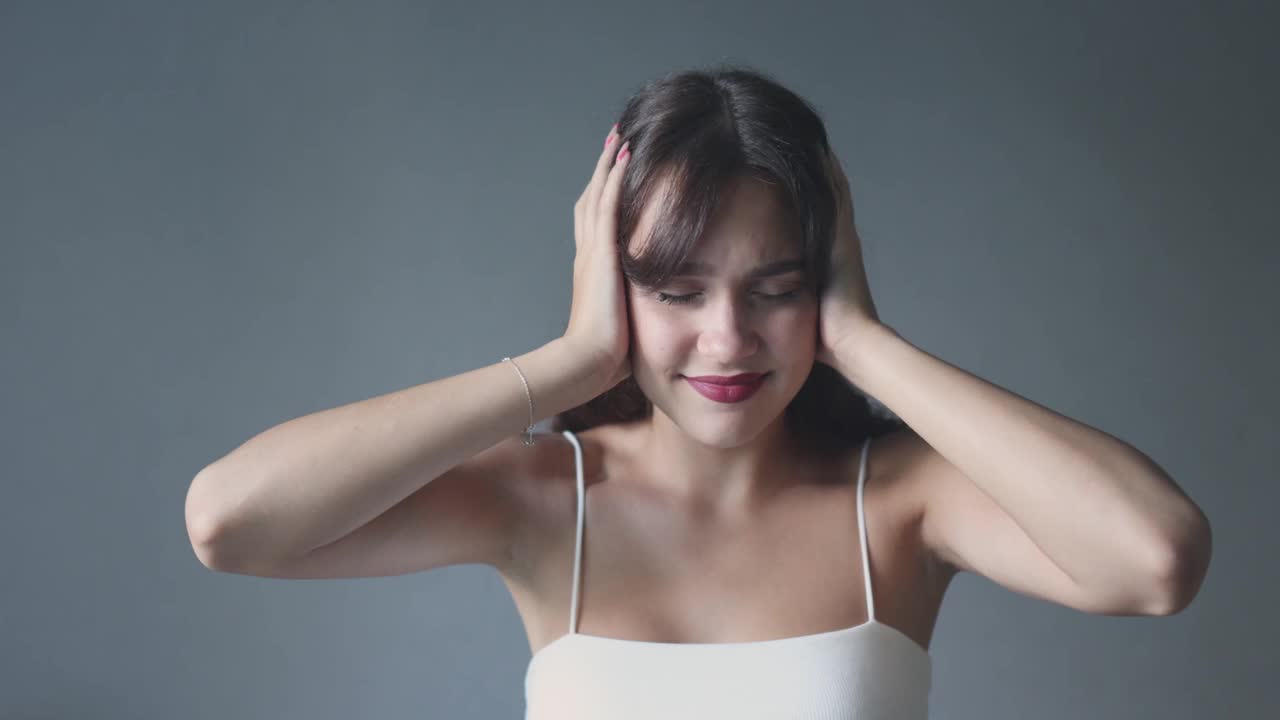 年轻漂亮的女人闭着耳朵，晃着眼睛，不听也听不见视频素材