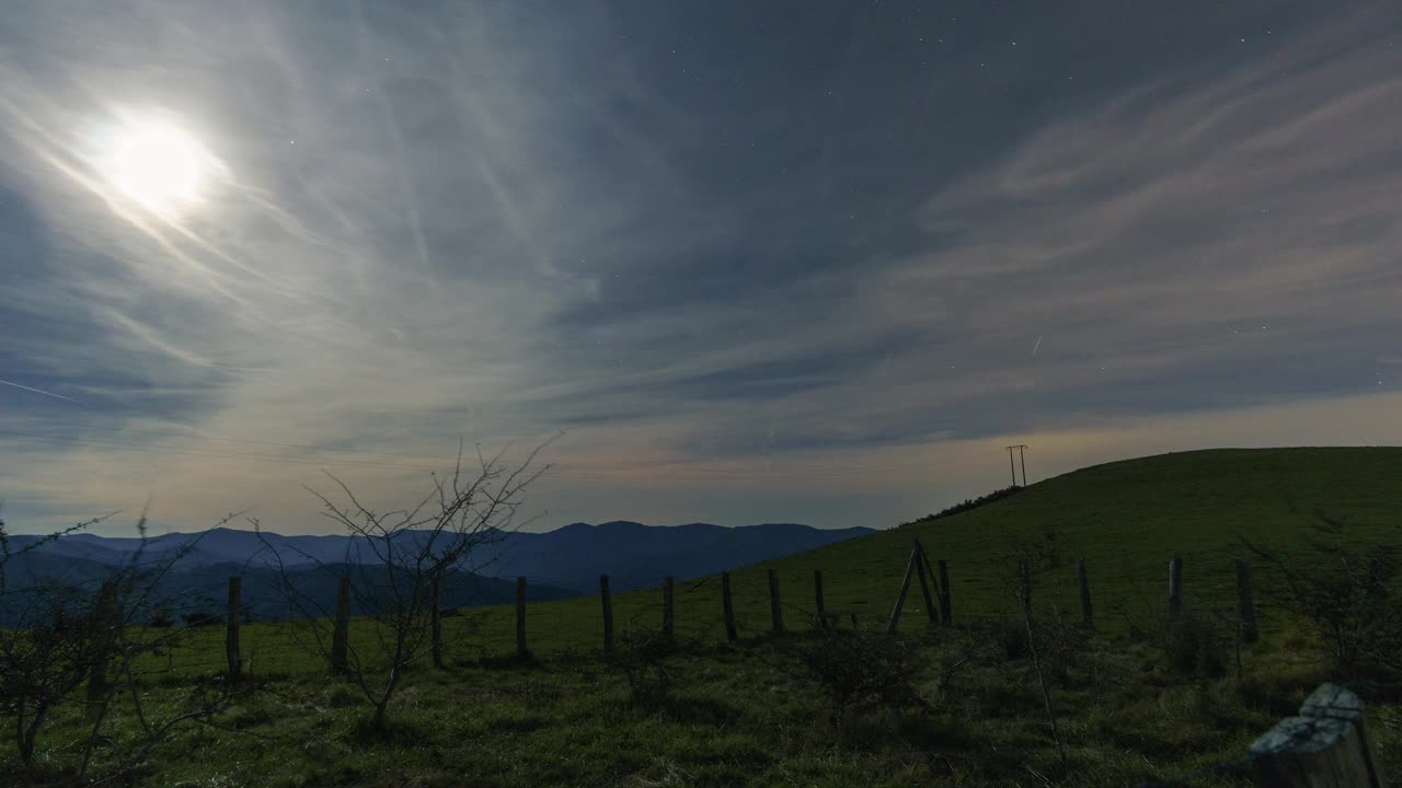 夜晚的天空时间流逝的星星和云与草地被月亮照亮，巴斯克国家，西班牙视频素材