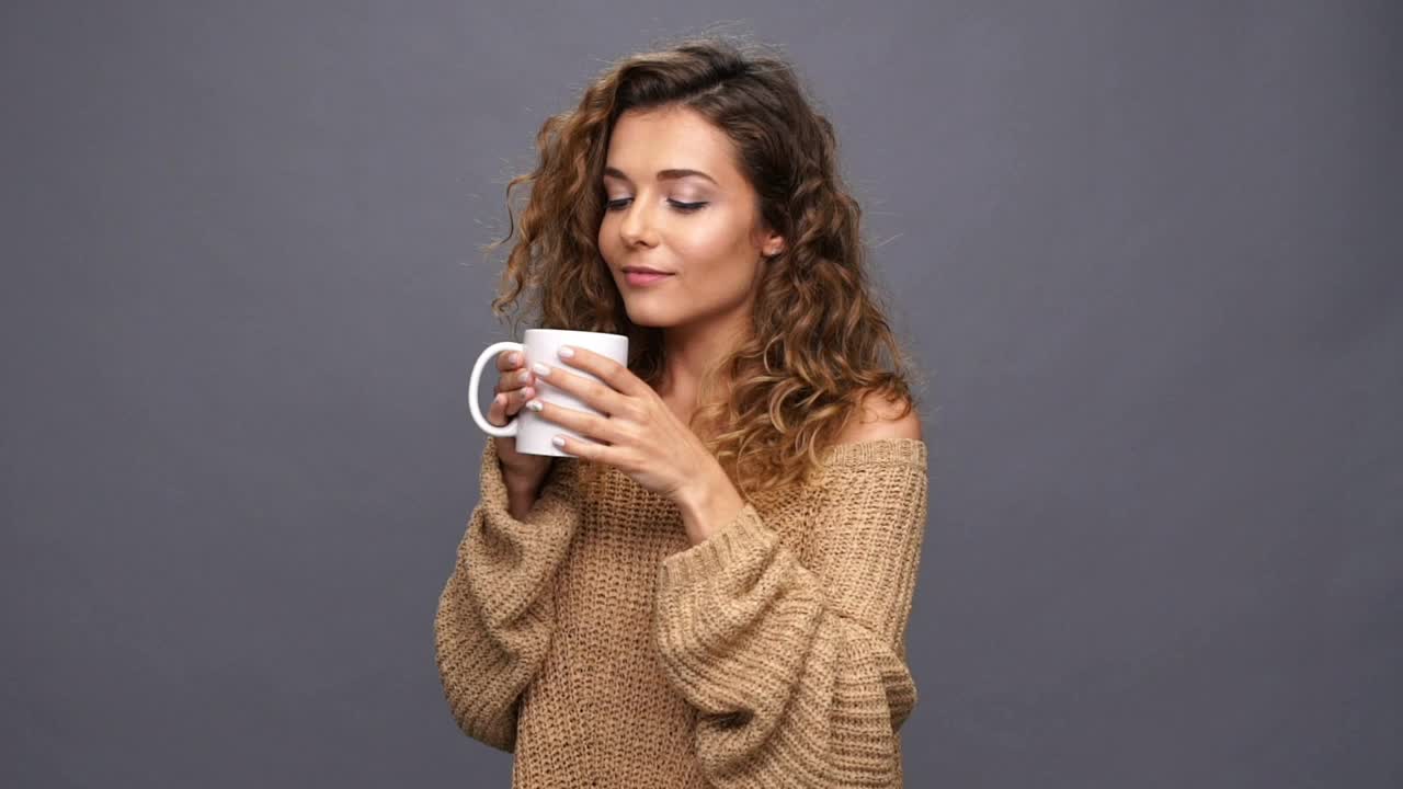 穿着毛衣的卷毛女人正在喝茶视频素材