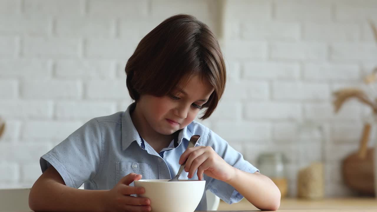 一个不开心的小男孩坐在厨房里没有胃口。视频素材