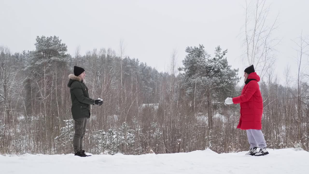 年轻的家庭在森林里放松和扔雪。幸福的情侣在雪地里飘雪视频素材