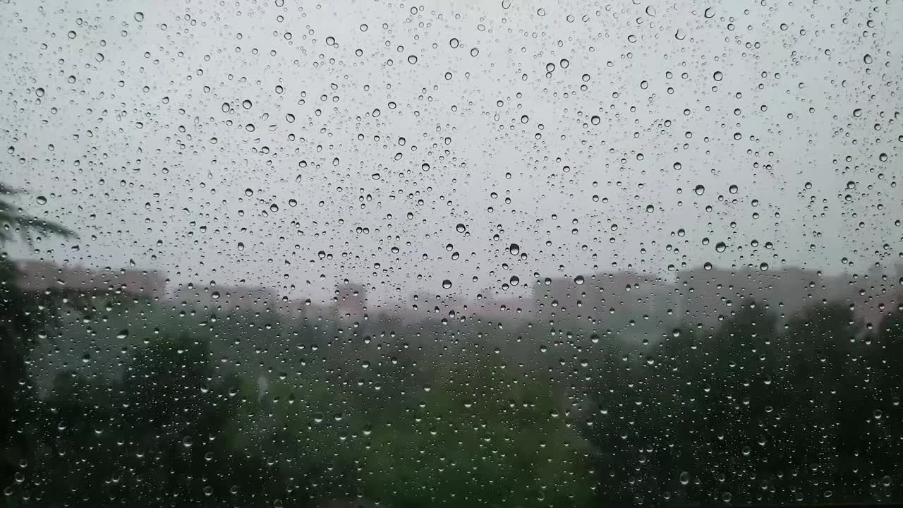 在城市的窗外下着雨。雨滴在玻璃上选择性聚焦。视频素材