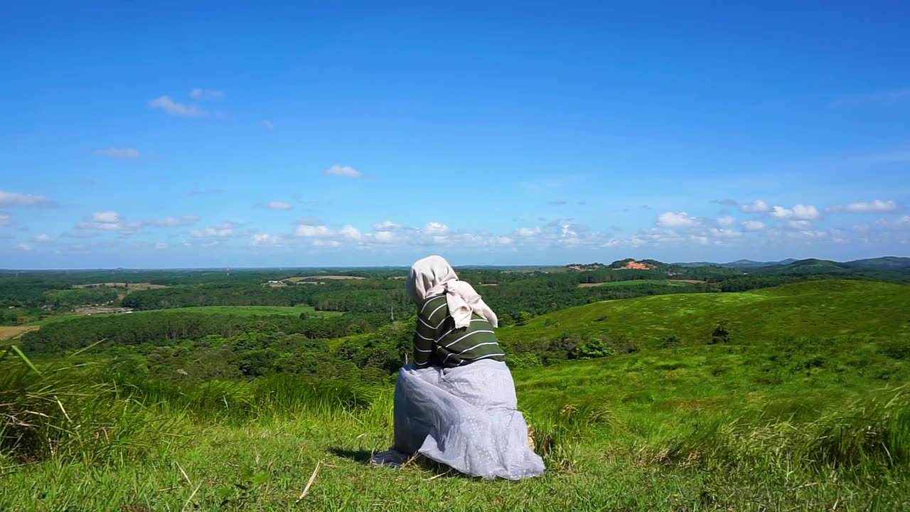 年轻的女人坐在山顶上，自由，放松视频素材画面1