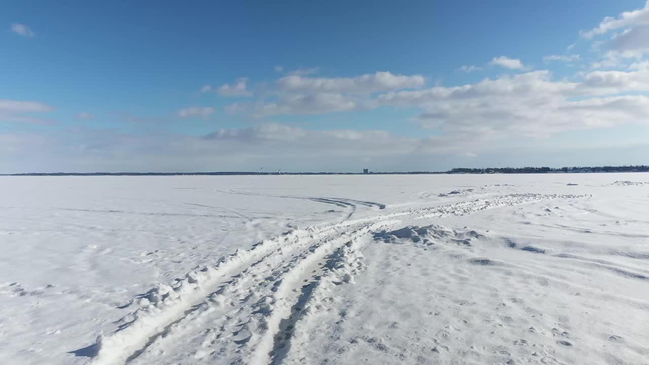 无人机一开始在雪地上飞得很低，然后上升得更高，显示风筝冲浪者在结冰的湖面上飞得更远视频素材