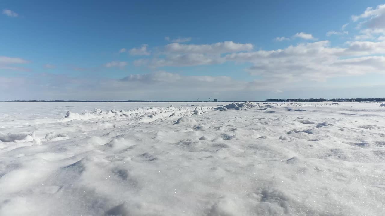 从地面上看，在雪地上，可以看到足迹，从远处看，在两山之湖的冰面上，风筝冲浪者视频素材