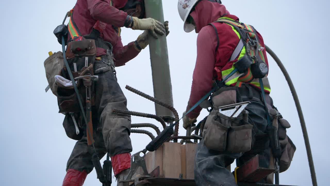 在一个大型商业工地，建筑工人将混凝土泵入水泥柱中视频素材