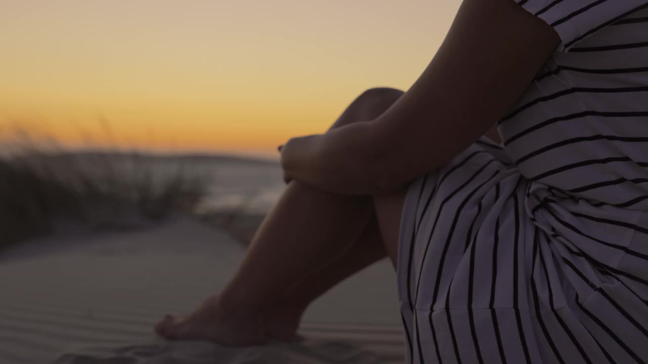 一个金发女人坐在海滩上，撒丁岛，意大利。视频素材