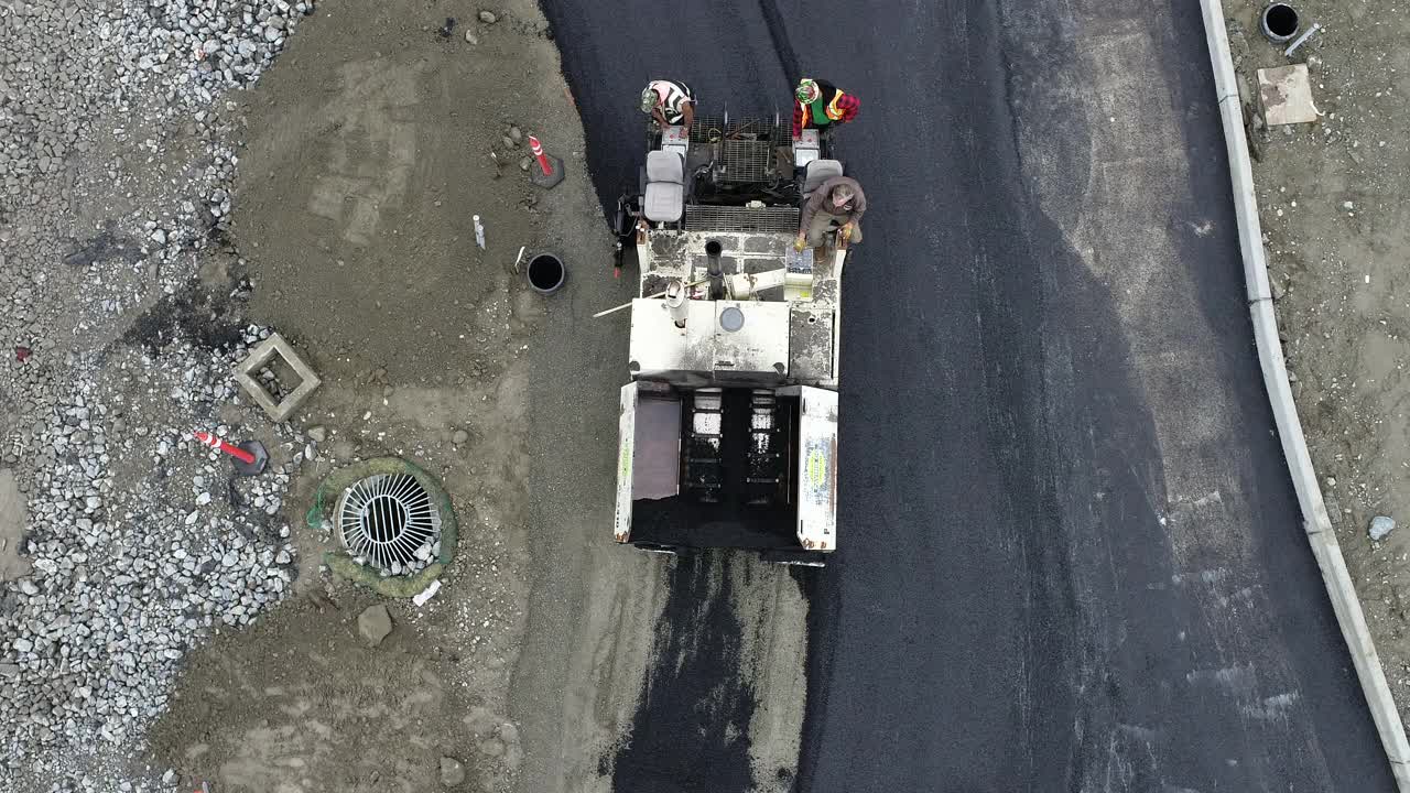 从空中俯瞰沥青铺路机安装道路在一个大型商业工地。视频素材