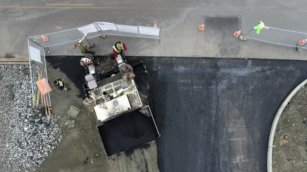 从空中俯瞰沥青铺路机安装道路在一个大型商业工地。视频素材