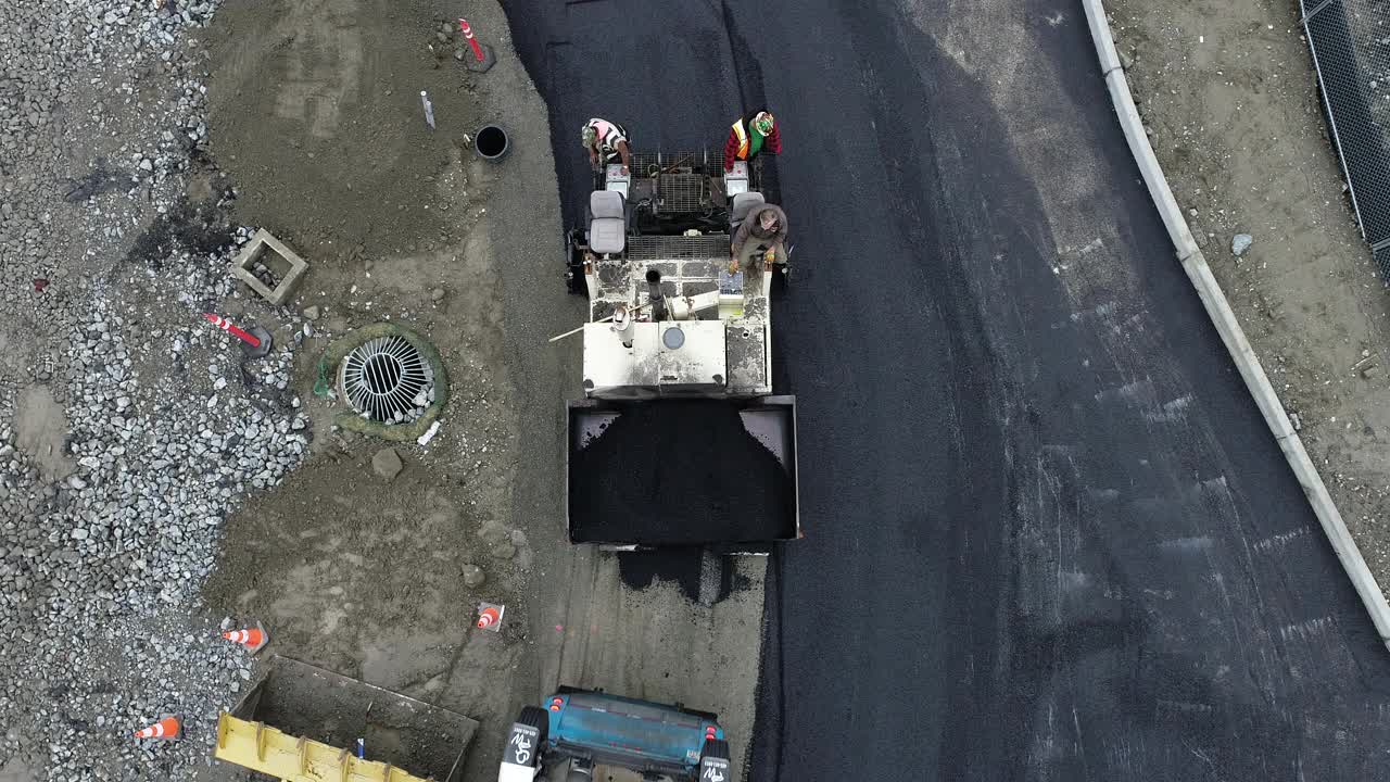 从空中俯瞰沥青铺路机安装道路在一个大型商业工地。视频下载