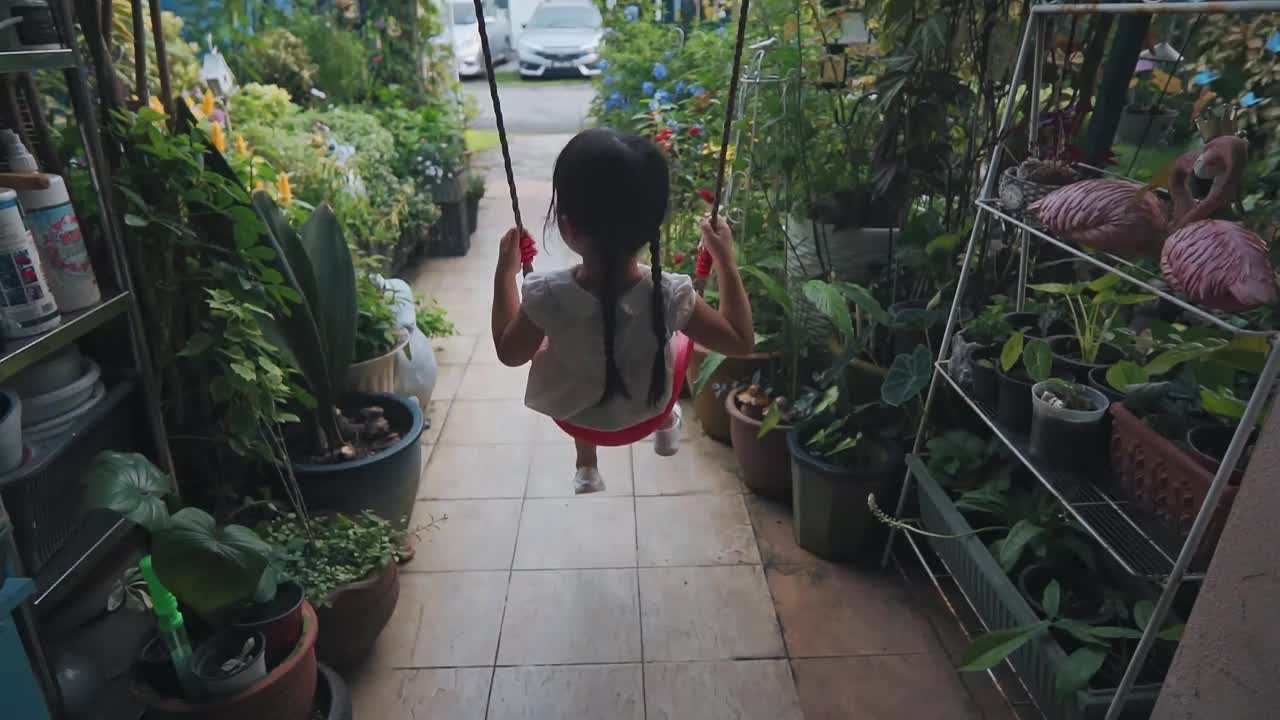 慢动作小女孩在她的前院房子在周末的闲暇时间独自玩秋千视频素材