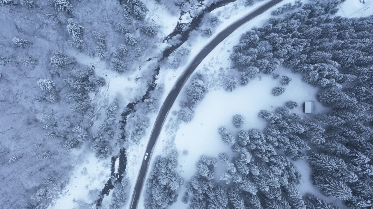 4K无人机镜头覆盖的冬季森林和道路在中间的汽车移动视频素材