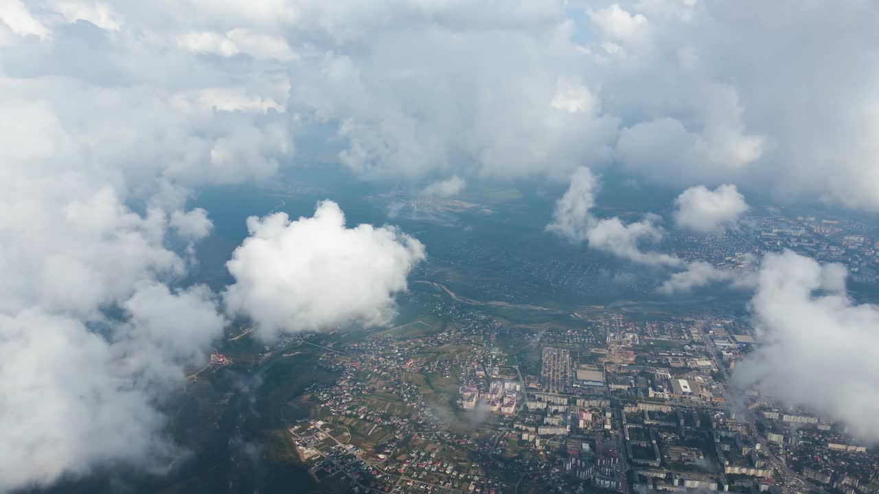 从高空的飞机窗口鸟瞰图，远处的城市被暴雨前形成的蓬松积云所覆盖视频素材