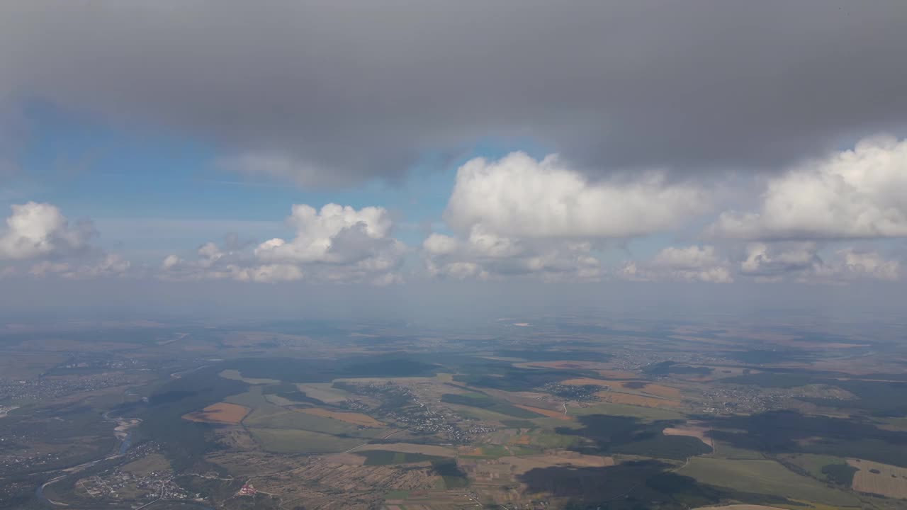 从高空的飞机窗口鸟瞰图，上面覆盖着暴雨前形成的蓬松积云视频素材