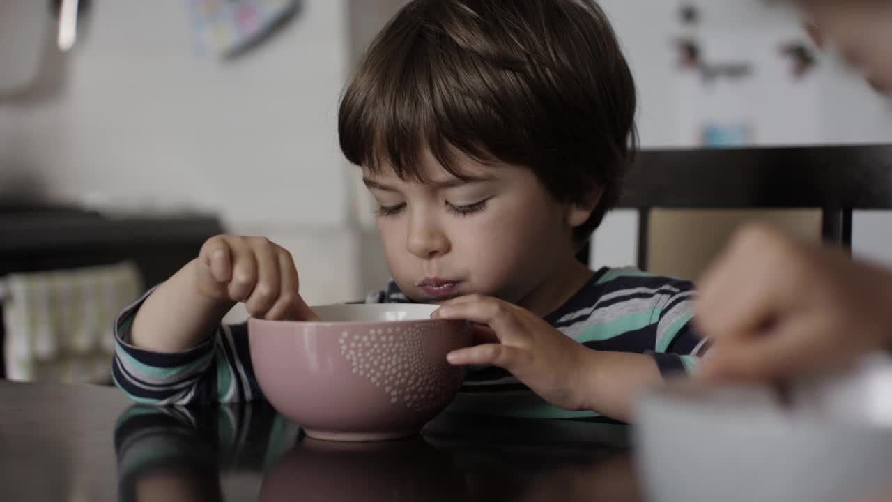 孩子吃牛奶玉米片。小饥饿的男孩坐在厨房的桌子上吃着早餐的玉米麦片。健康的营养片。孩子的肖像吃早餐吃什锦麦片视频素材