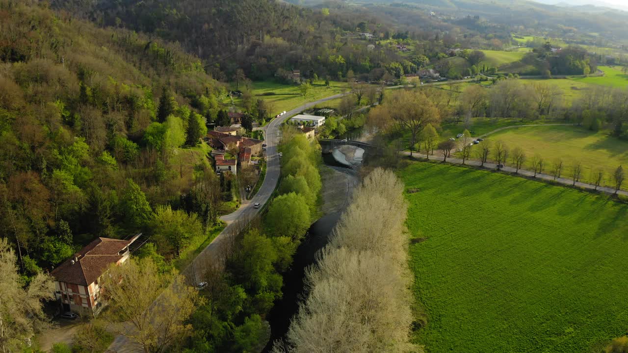 空中下降的美丽镜头的道路由住宅，无人机飞行向前越过河流-亚平宁山脉，意大利视频素材