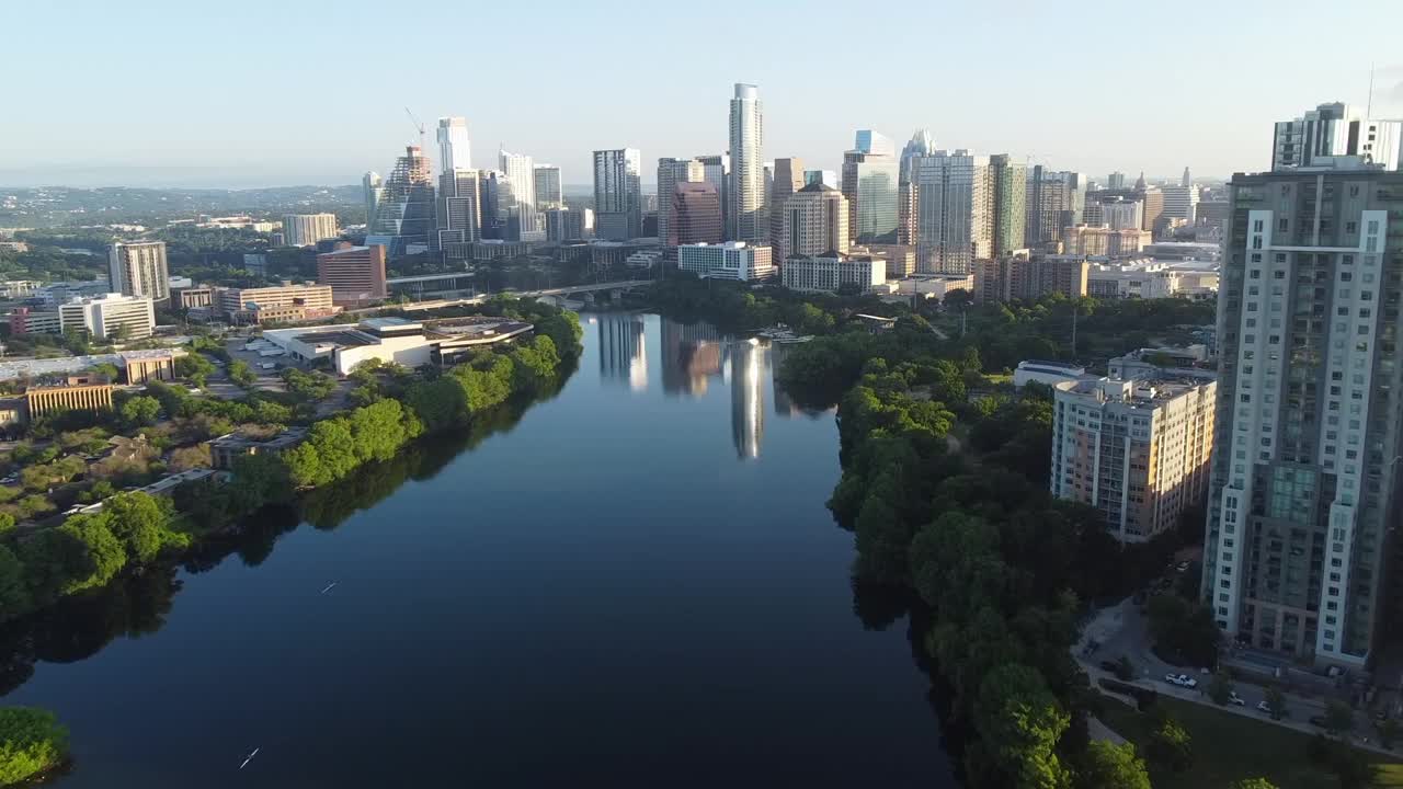 现代建筑在科罗拉多河上的倒影航拍，无人机在阳光明媚的日子在城市上空向前飞行-奥斯汀，德克萨斯州视频素材