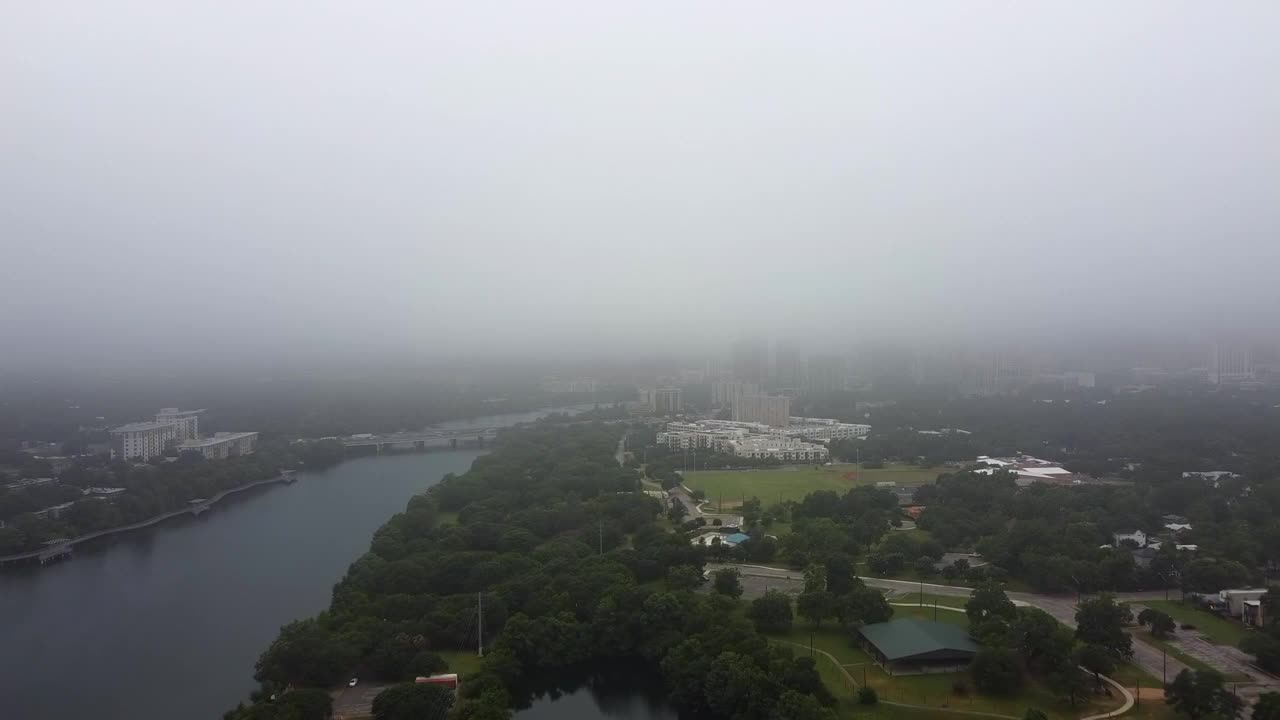 空中拍摄科罗拉多河和城市上空的大雾天气，无人机飞向现代建筑附近的桥梁-奥斯汀，德克萨斯州视频素材