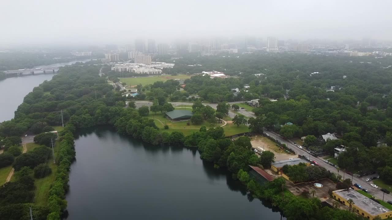 雾天下的城市和科罗拉多河的航拍，无人机正向现代建筑飞去——奥斯汀，德克萨斯州视频素材