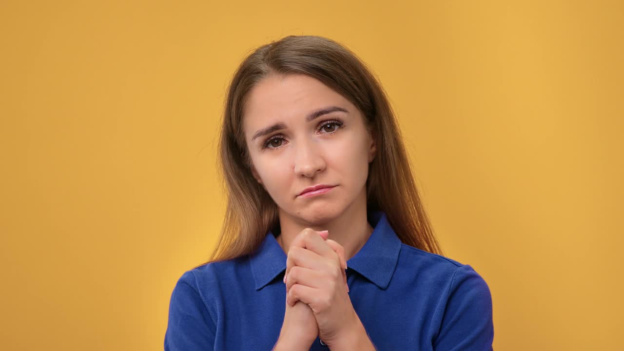 特写希望宽恕的金发女人祈祷请连接的手摆孤立的橙色视频素材