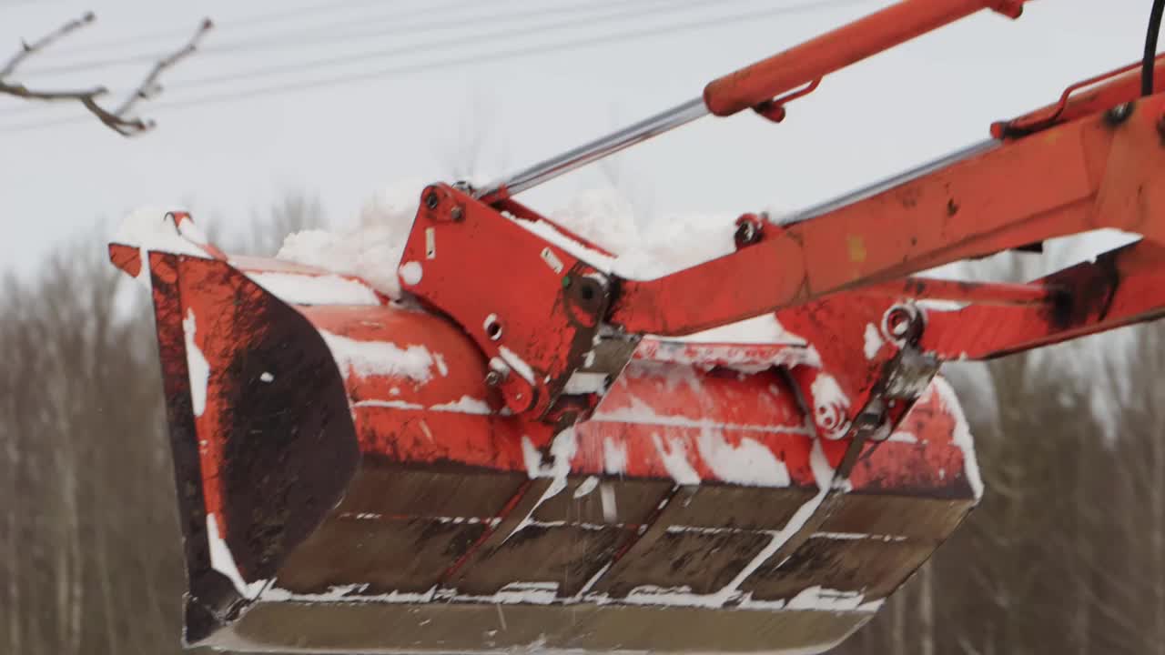 一辆带着黄色铲斗的拖拉机在冬天清除街上的积雪。道路清洁援助，工业视频素材