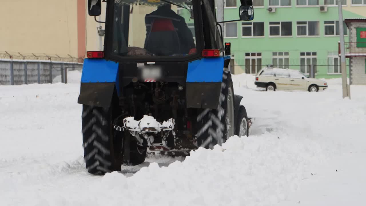 拖拉机在下雪的冬季城市清理雪山，工业视频素材