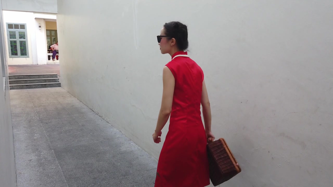 中国年轻女性时装模特在旅行者主题复古中国旗袍走过一个小建筑小巷。视频素材画面2