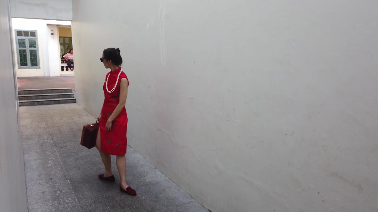 中国年轻女性时装模特在旅行者主题复古中国旗袍走过一个小建筑小巷。视频素材画面4