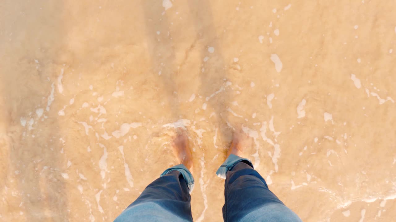 海浪冲刷着男人的脚，年轻的印度男子站在海边，享受着旅途中的海潮，盖伊在海边享受暑假。俯视图POV在印度古吉拉特邦的Shivrajpur海滩视频素材