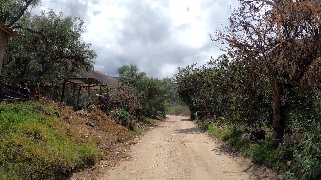 在蓝天白云的日子里，驱车前往帕隆泻湖，在树木和山丘之间的土路上行驶视频素材