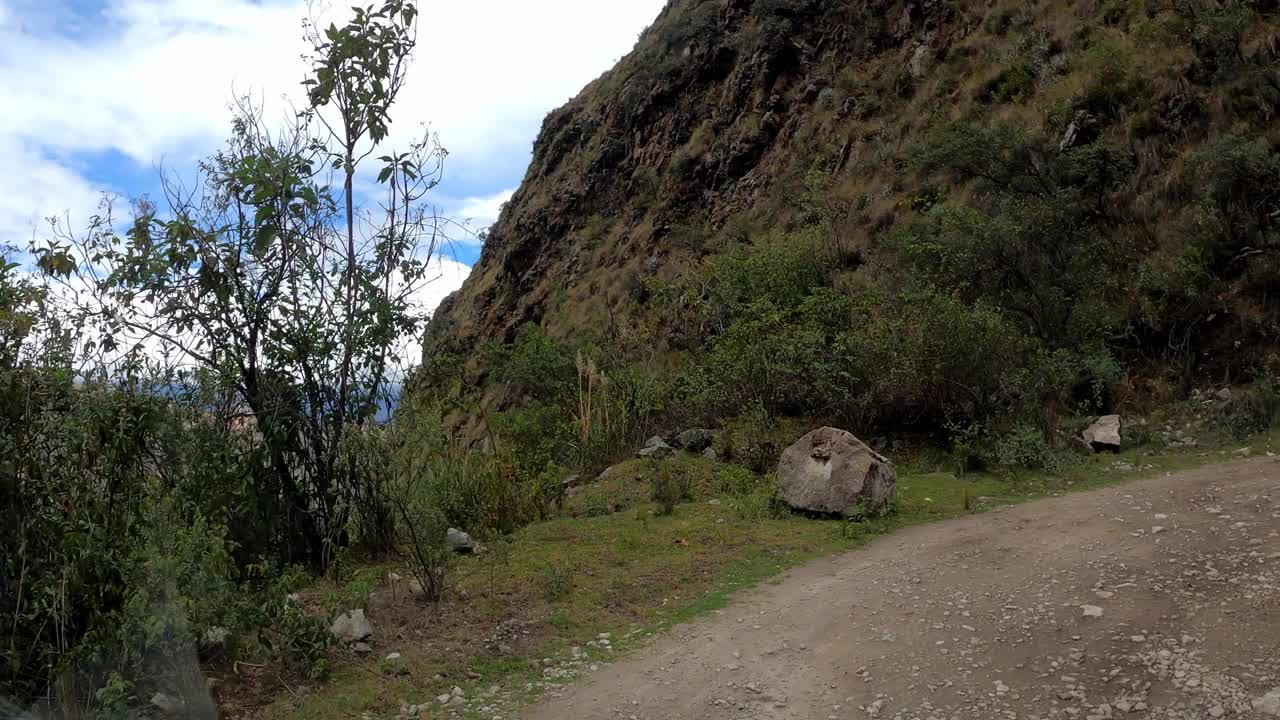 在蓝天白云的日子里，驱车前往帕隆泻湖，在树木和山丘之间的土路上行驶视频素材