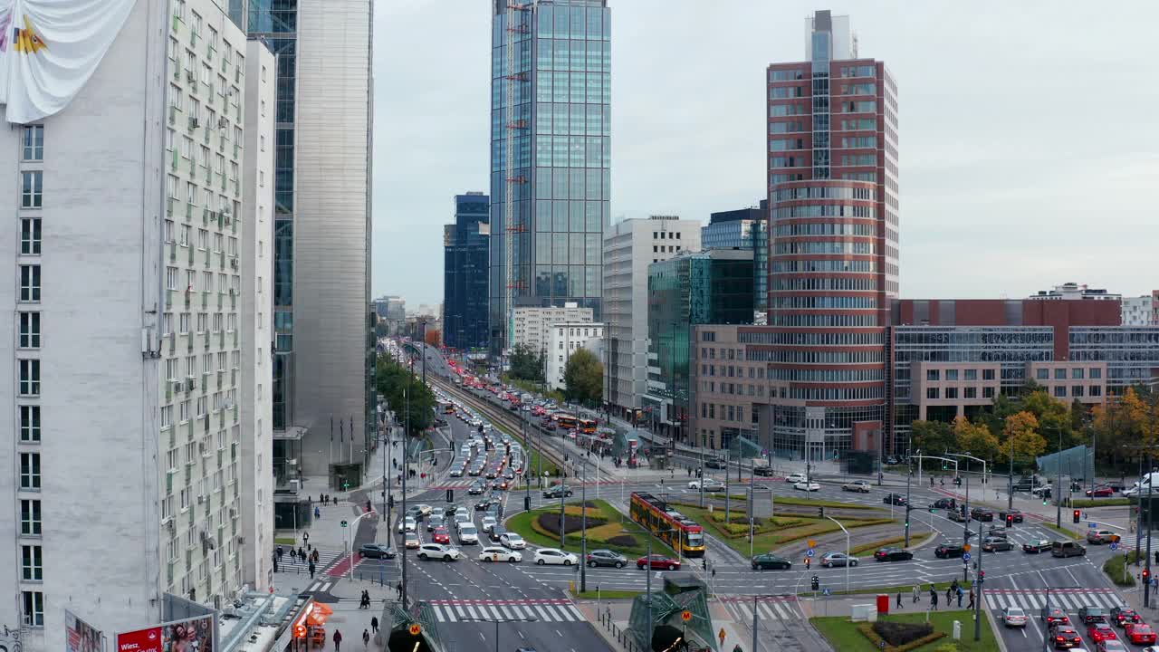 在市中心多车道繁忙道路上的大型环形线路的高架镜头。电车停在十字路口内。周围都是高大的现代建筑。波兰华沙视频素材