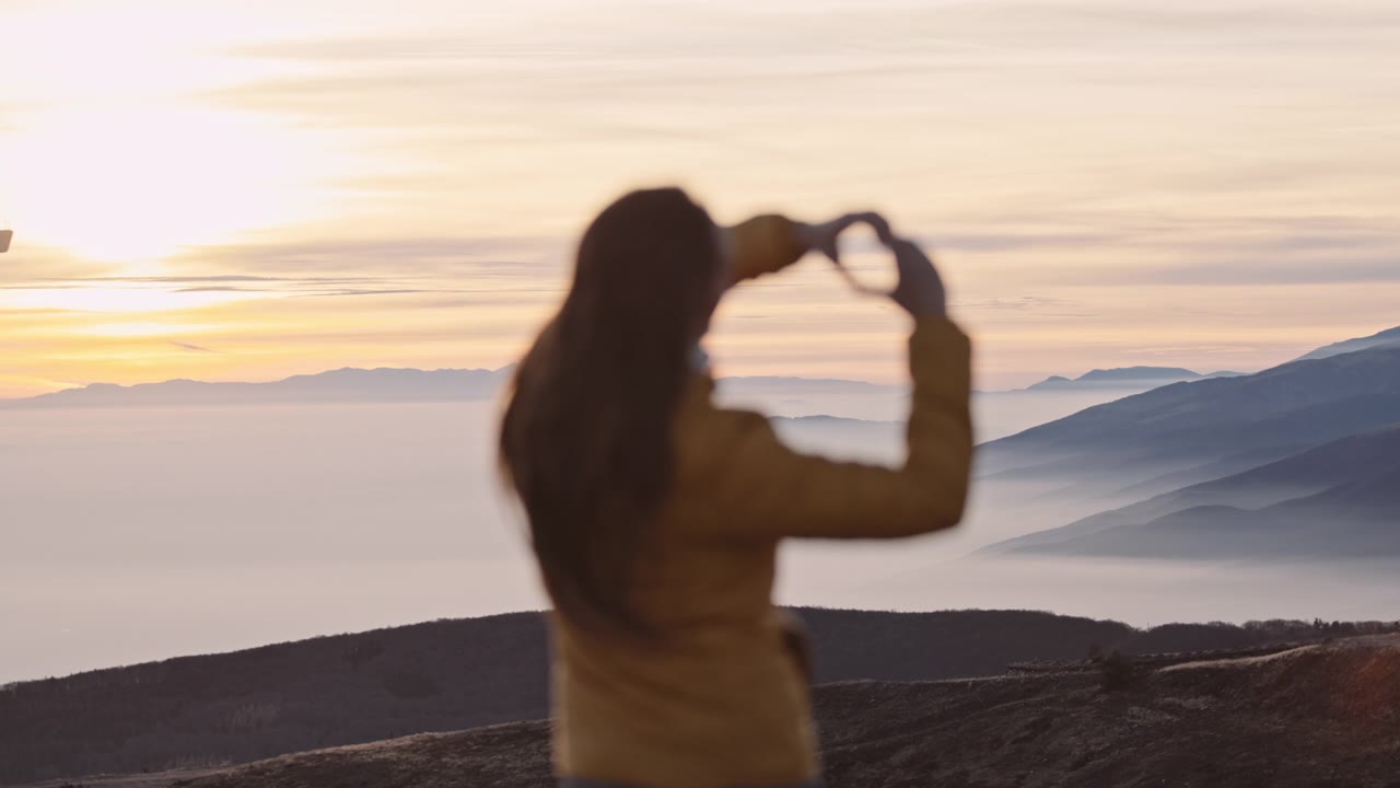 在山峰上的女人在云上享受日落。崇高的观点。视频素材画面1