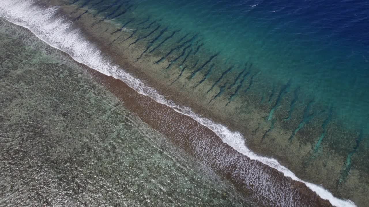 一架无人机飞越平静的海洋与珊瑚礁热带天堂岛的鸟瞰图。令人惊叹的自然景观，蓝色的泻湖和太平洋。视频下载