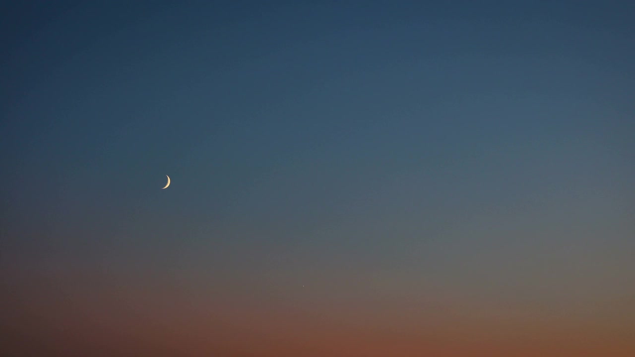 夜晚河岸上城市建筑上方的半月视频素材