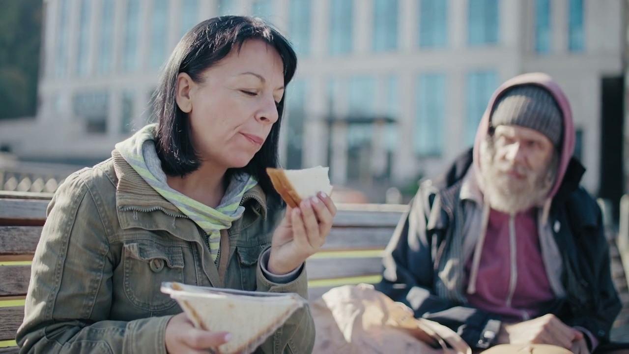 可怜的男人看着女人吃三明治，缺少食物，社会不公视频素材