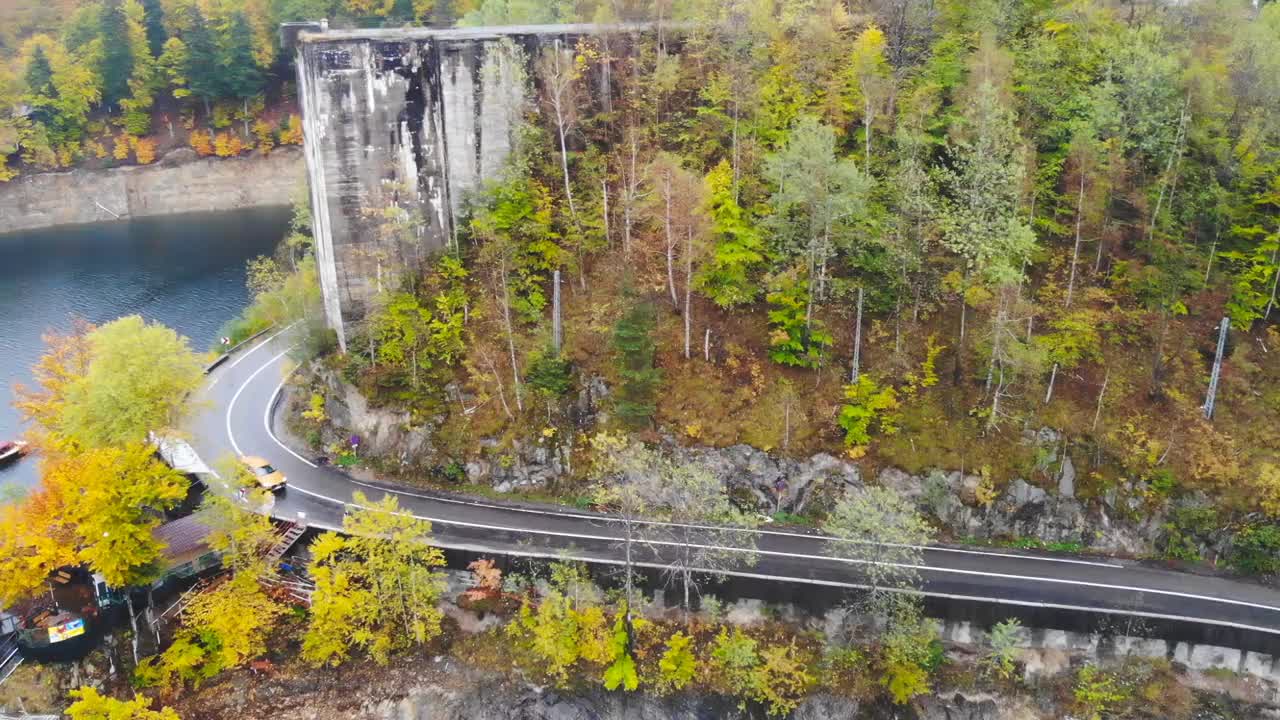 在雾蒙蒙的乡间小路上，汽车在桥上行驶。在秋天山路上的堤坝上骑车。航拍越野车通过风景秀丽的风景道。汽车旅行的概念。俯视图视频素材