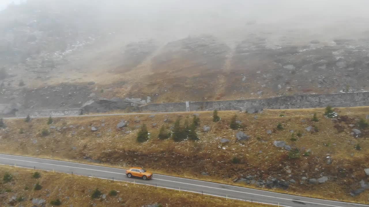 橙色的汽车在秋天的雾山道路上行驶。秋日乡村公路上的汽车航拍。越野车穿过风景秀丽的风景道。旅行的概念。俯视图视频素材