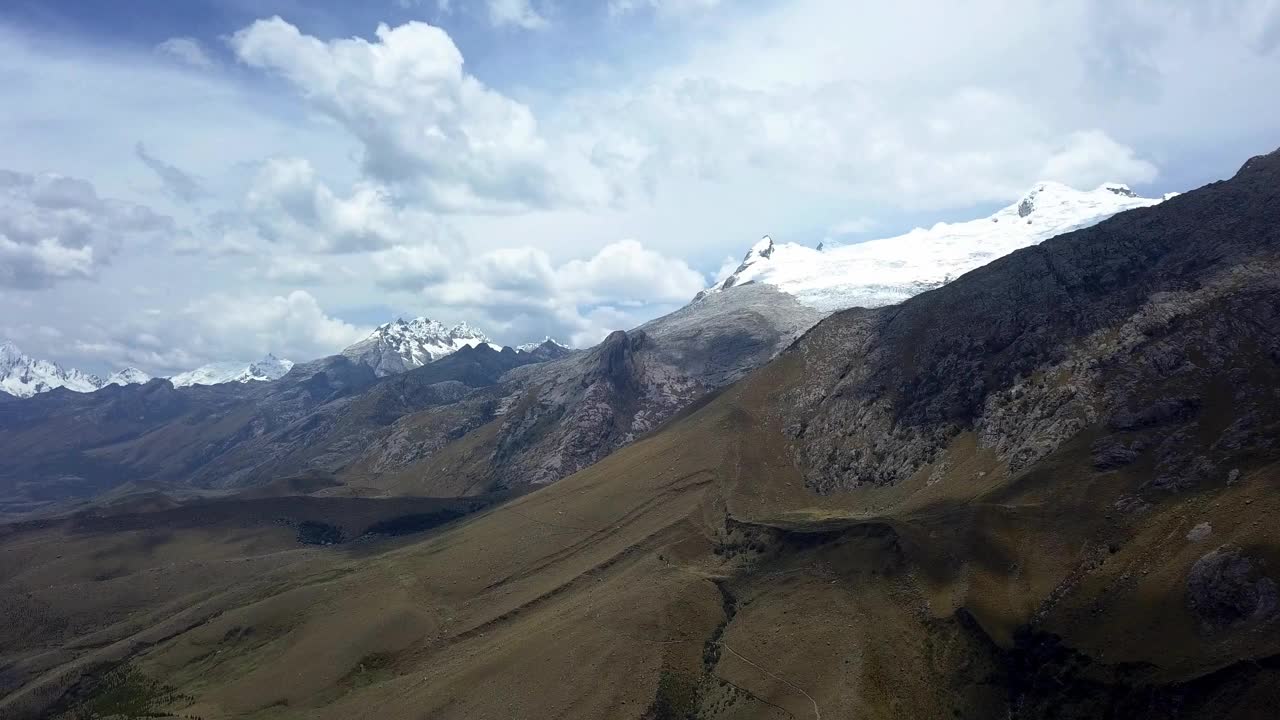 无人机从上方拍摄的秘鲁华拉兹高地的Radian泻湖上的几座积雪覆盖的山脉视频素材