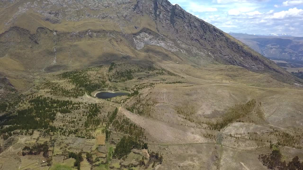 无人机拍摄的梨形泻湖被山脉和树木包围，旁边是巨大的云阴影。秘鲁瓦拉兹高地的弧度视频素材