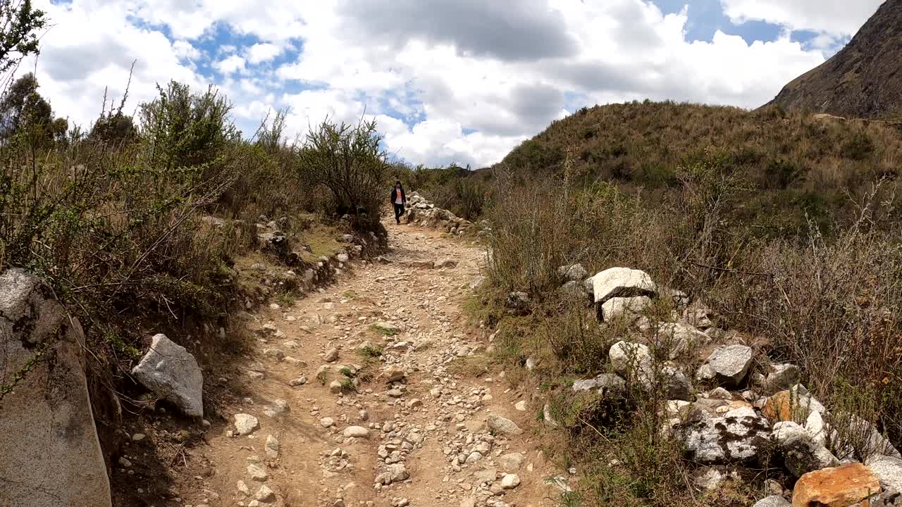 用第一人称观看一位朋友在秘鲁瓦拉兹高地的一座山上徒步沿着陡峭的岩石和泥土小路走下去视频素材