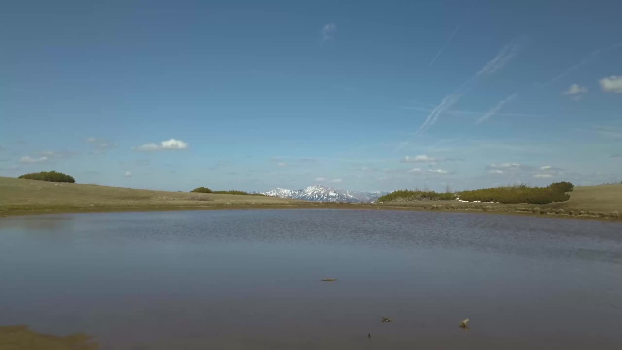 无人机在湖面和雪地上空飞行，展现出山景视频素材