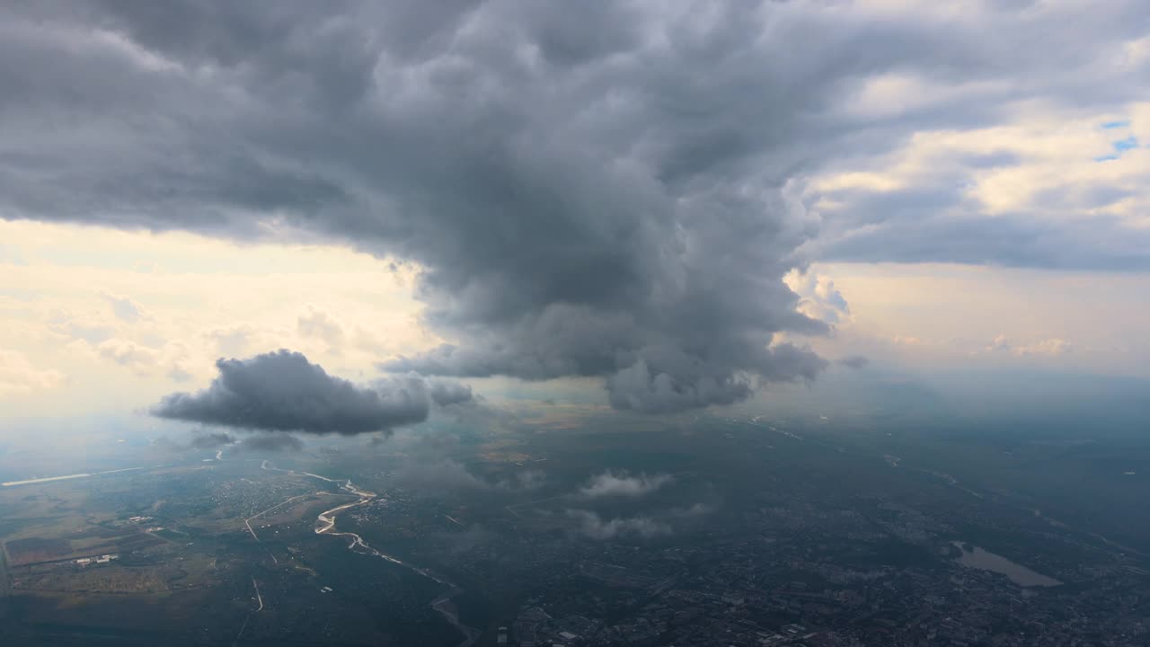 从飞机窗口俯瞰，远处城市在暴风雨前被蓬松的积云覆盖视频素材