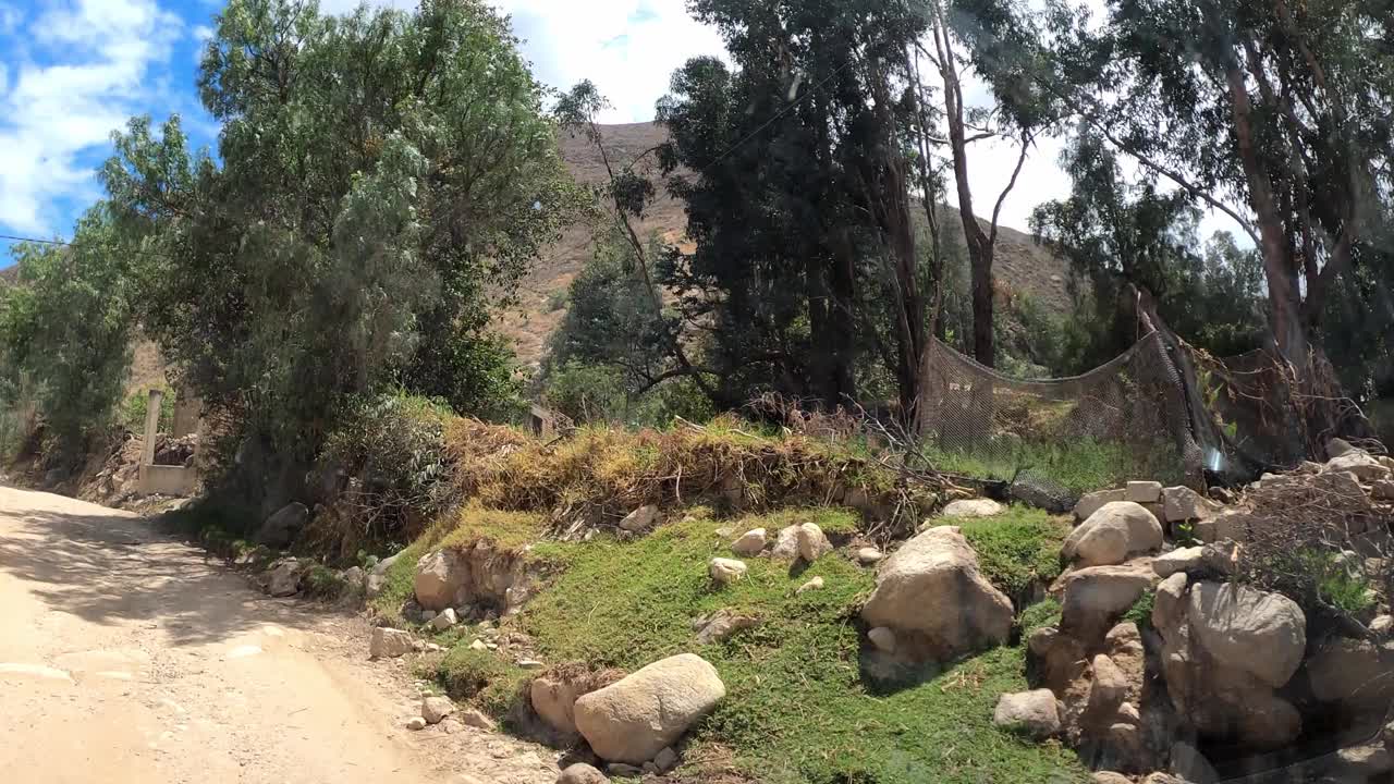 在蓝天白云的日子里，驱车前往帕隆泻湖，在树木和山丘之间的土路上行驶视频素材