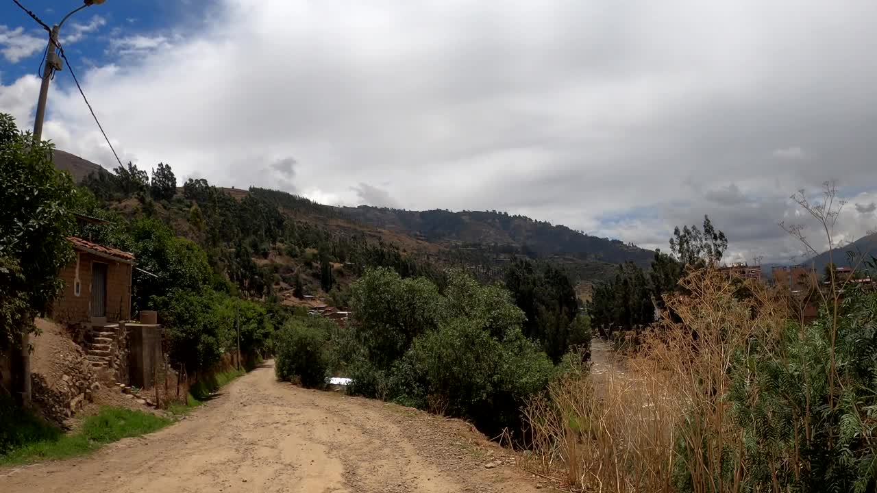 白天，在秘鲁瓦拉兹高地的树木、山脉和房屋之间奔跑的第一人称视角视频素材