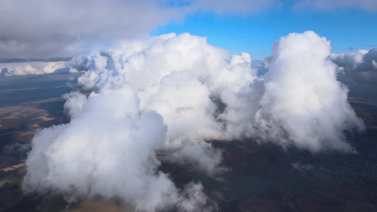 高空从飞机窗口俯瞰被暴雨前形成的蓬松积云覆盖的地面视频素材